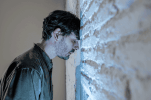 a man standing leans his forehead on a wall while struggling to understand the various schizophrenia types