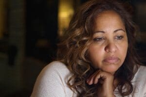 concerned woman stares off in the distance while wondering how to help someone with ptsd