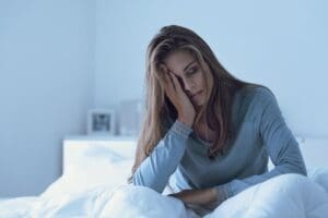 woman sits up in bed holding her hand to the side of her face and wonders if spravato has side effects