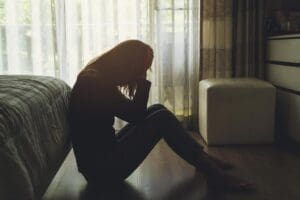 a person sits on the floor of their bedroom struggling with understanding what are intrusive thoughts