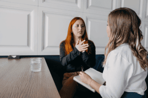 a woman with high-functioning autism speaks with her specialist as her specialist takes notes in notebook