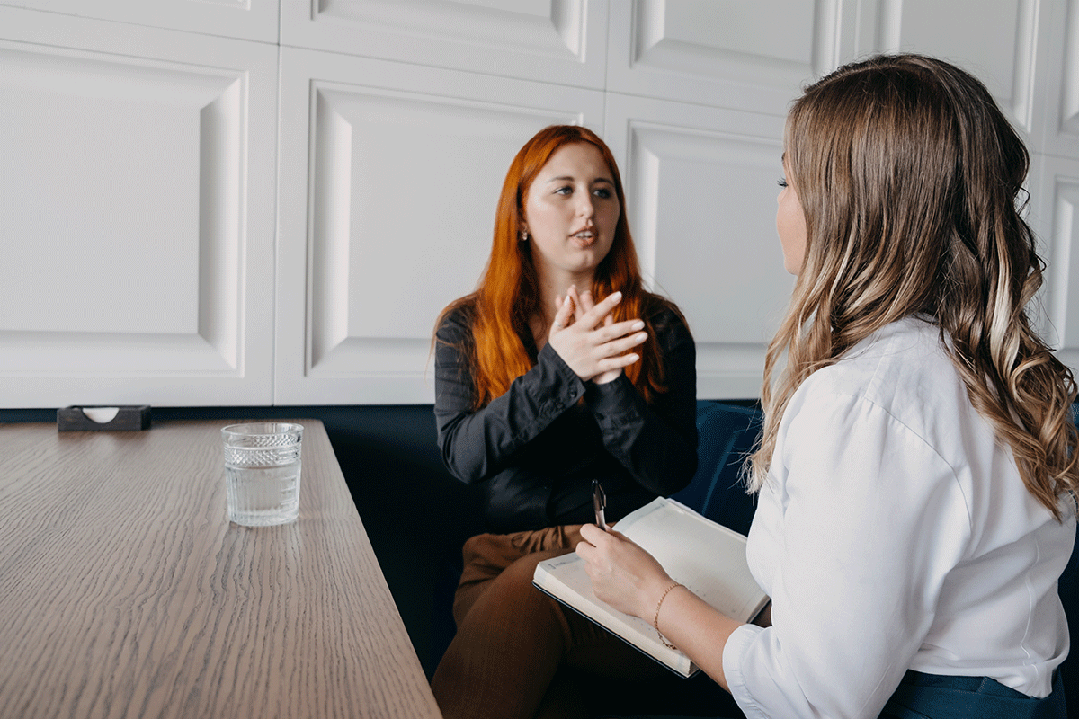a woman with high-functioning autism speaks with her specialist as her specialist takes notes in notebook