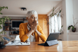 woman sits at table with her tablet searching the connection between stress management techniques and how to get help