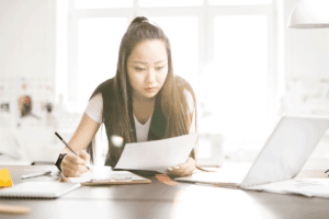 a woman sits at a desk with a pencil in one hand and paperwork in the other and asking herself what is the connection between adhd and hyperfocus