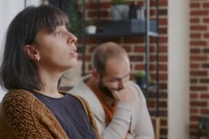 a woman looks off into the distance while a man leans into his hand and thinks about how to process anger