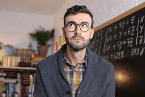 a man wearing glasses and cardigan looks up and thinks about the connection between adhd and anxiety