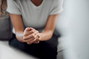 woman sits and is holding her hands together thinking about the connection between depression and laziness
