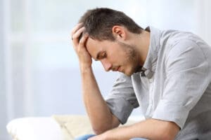 struggling man holds his hand to his forehead wondering if he has clinical depression